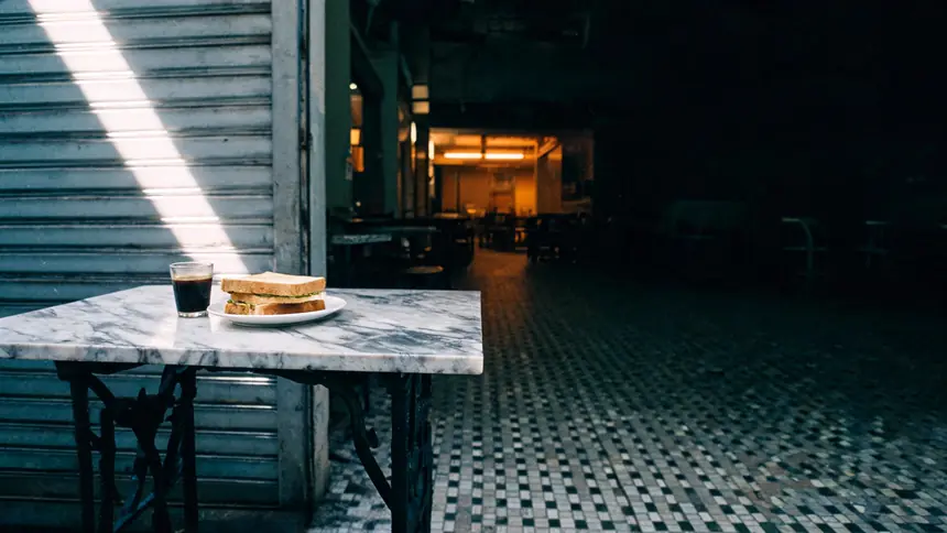 A marble-top kopitiam table at opening time, kopi and kaya toast in the morning light.
