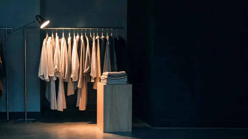 A single rail of clothes under one warm spotlight in a small boutique after closing.